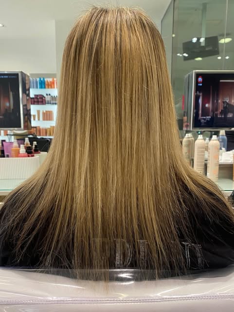 Capelli lisci biondo dorato visti di spalle in salone, schiariture sottili distribuite su tutta la lunghezza e punte pari.