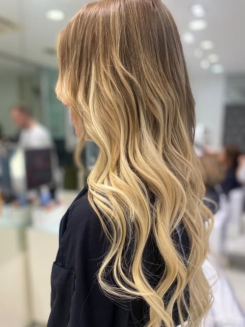 Capelli biondi molto lunghi visti di profilo, onde definite dalle orecchie alle punte e radici piu scure sfumate.